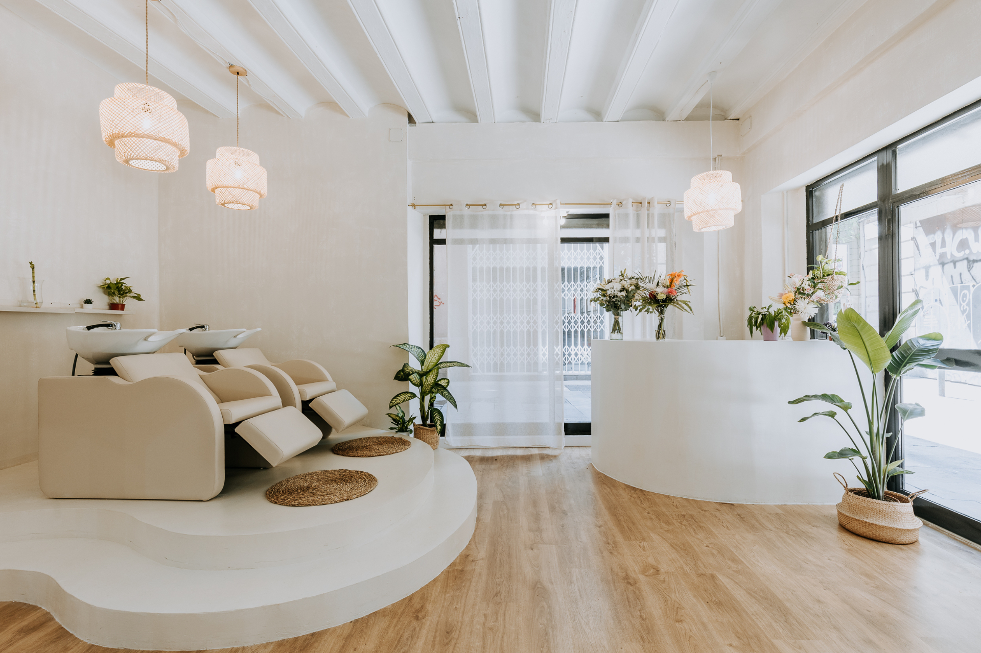 Wave Studio salon interior — warm beige tones with rattan pendants and lush greenery